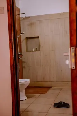 a bathroom with a toilet and a door open at Avana Home in Arusha