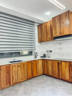 a kitchen with wooden cabinets and a window at Valonia Apartments in Arusha