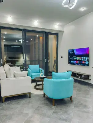 a living room with two chairs and a tv at Valonia Apartments in Arusha