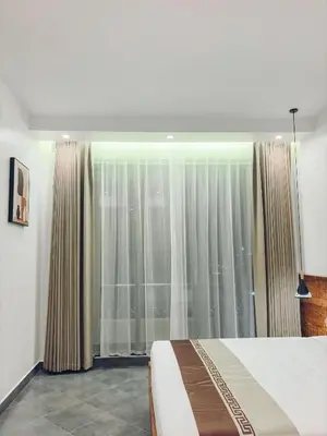 a bedroom with a bed and a large window at Valonia Apartments in Arusha