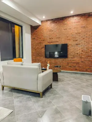 a living room with a couch and a tv on a brick wall at Valonia Apartments in Arusha