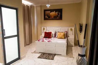 a bedroom with a white bed with pillows on it at lioness villa homestay in Arusha