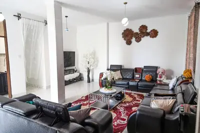 a living room with black leather couches and a red rug at lioness villa homestay in Arusha