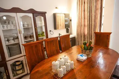 a wooden dining room table with a cabinet with dishes on it at lioness villa homestay in Arusha
