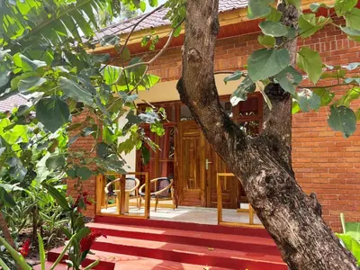 a brick house with a wooden door next to a tree at Arusha Explorers Lodge in Themi