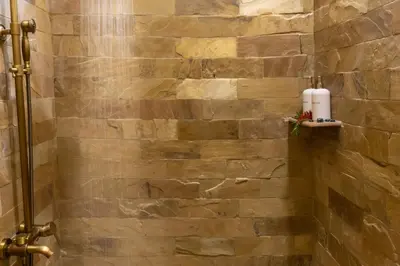 a stone wall in a bathroom with a shower at Arusha Explorers Lodge in Themi