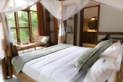 a bedroom with a large bed with white sheets and pillows at Arusha Explorers Lodge in Themi