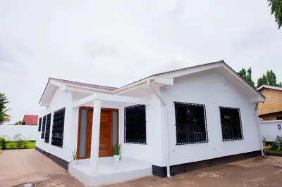 a white house with black barred windows at Enamour Moshi in Moshi