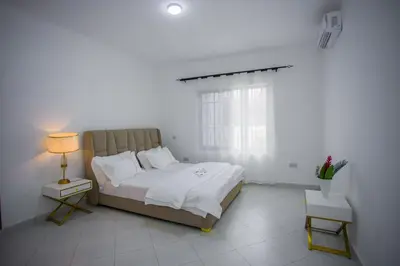 a white bedroom with a bed and a window at Enamour Moshi in Moshi