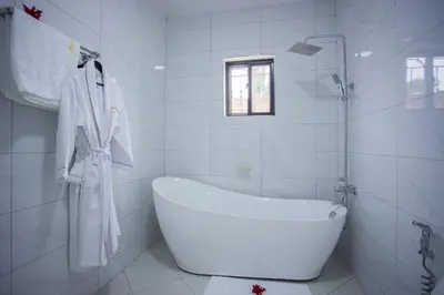 a white bathroom with a tub and a window at Enamour Moshi in Moshi