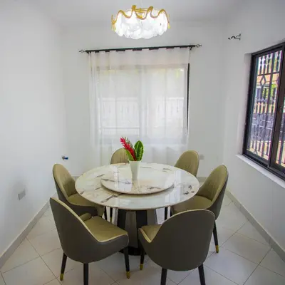 a dining room with a round table and chairs at Enamour Moshi in Moshi