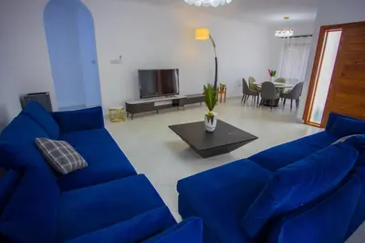 a living room with a blue couch and a tv at Enamour Moshi in Moshi