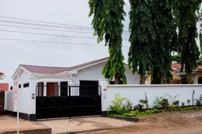 a white house with a black gate at Enamour Moshi in Moshi