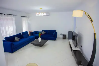 a living room with a blue couch and a tv at Enamour Moshi in Moshi