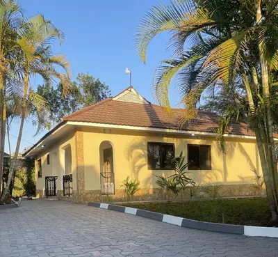 a yellow house with palm trees in front of it at Rhovee Arusha in Arusha