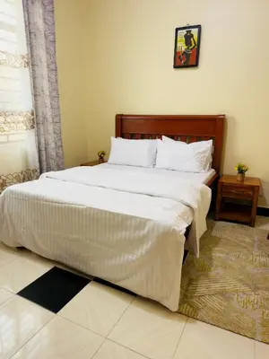 a bedroom with a large bed with white sheets at Fatoosh Nest in Arusha
