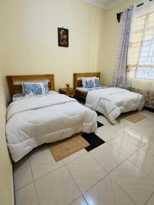 a bedroom with two beds and a window at Fatoosh Nest in Arusha