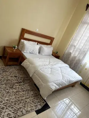 a bedroom with two beds with white sheets and a rug at Fatoosh Nest in Arusha