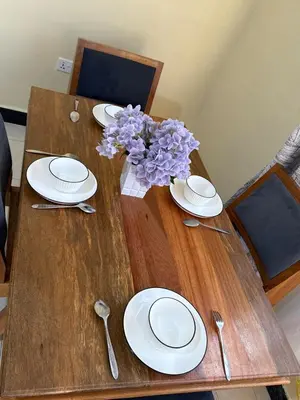 a wooden table with plates and a vase of purple flowers at Fatoosh Nest in Arusha