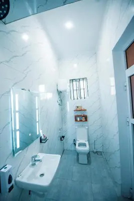 a white bathroom with a sink and a toilet at Heaven Hill Apartments - Arusha in Arusha