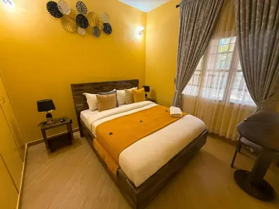 a bedroom with a bed and a window and a chair at Nice & Slow Homes in Arusha