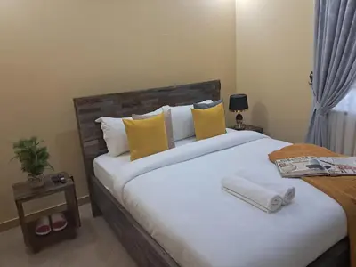 a bedroom with a large bed with yellow pillows at Nice & Slow Homes in Arusha