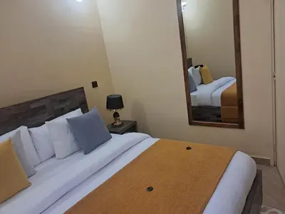 a bedroom with a large bed and a mirror at Nice & Slow Homes in Arusha