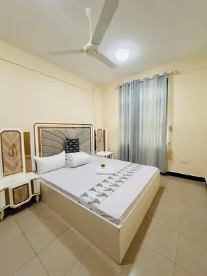 a large bed in a room with a ceiling fan at QD Apartment in Arusha