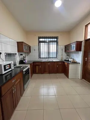 a large kitchen with wooden cabinets and a window at QD Apartment in Arusha