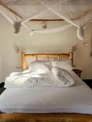 a white bed with white sheets and pillows at Kilimanjaro Kwetu Homestay in Moshi