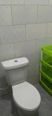 a bathroom with a white toilet and green shelves at Leadway Park Moshi Kilimanjaro in Moshi