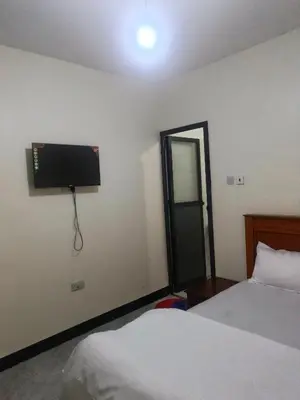 a bedroom with two beds and a television on the wall at Old Moshi Park in Arusha
