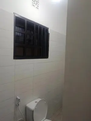 a bathroom with a toilet with a window above it at Old Moshi Park in Arusha