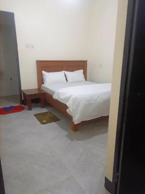 a bedroom with a bed with a white sheets and a table at Old Moshi Park in Arusha