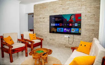 a living room with a tv on a brick wall at The Nook at Njiro 39 - 3BR by Kyada Stays in Arusha