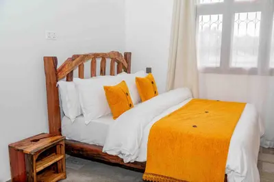 a bed with orange and white pillows and a window at The Nook at Njiro 39 - 3BR by Kyada Stays in Arusha