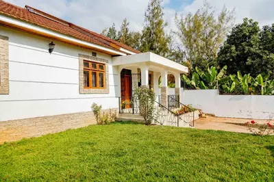 a white house with a red door and a yard at The Nook at Njiro 39 - 3BR by Kyada Stays in Arusha