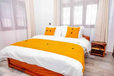 a bedroom with a large bed with orange and white pillows at The Nook at Njiro 39 - 3BR by Kyada Stays in Arusha