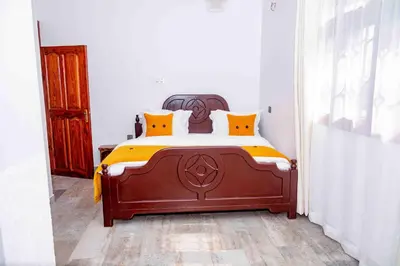 a bedroom with a wooden bed with orange pillows at The Nook at Njiro 39 - 3BR by Kyada Stays in Arusha