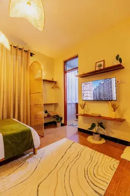 a bedroom with a bed and a flat screen tv at Serene and Amara By Tadre House's in Arusha