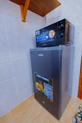 a small refrigerator with a microwave on top of it at Serene and Amara By Tadre House's in Arusha