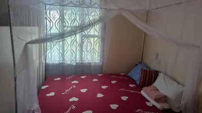 a bedroom with a bed with a red comforter and a window at Lake natron Naibala Bed&Breakfast in Mtowabaga