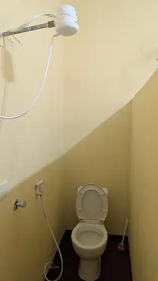 a bathroom with a toilet with a light on the wall at Lake natron Naibala Bed&Breakfast in Mtowabaga