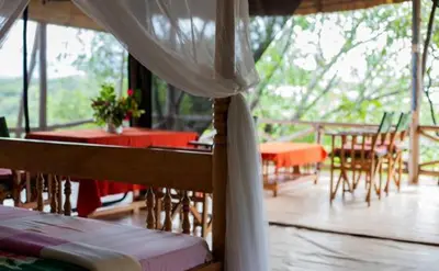 a room with a porch with a table and chairs at Havennature Safari Camp and Lodge in Namalulu
