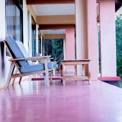 a rocking chair and a table on a porch at Havennature Safari Camp and Lodge in Namalulu