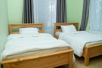 two twin beds in a room with curtains at Rest and Stay Minutes from Kilimanjaro Airport in Arusha