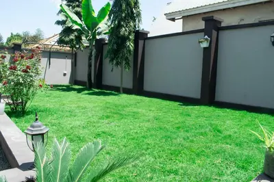 a backyard with white fence and green grass at Rest and Stay Minutes from Kilimanjaro Airport in Arusha