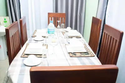 a long table with chairs and a table with plates and glasses at Rest and Stay Minutes from Kilimanjaro Airport in Arusha