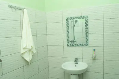 a white bathroom with a sink and a shower at Rest and Stay Minutes from Kilimanjaro Airport in Arusha