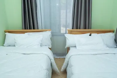 two beds in a room with white sheets and pillows at Rest and Stay Minutes from Kilimanjaro Airport in Arusha